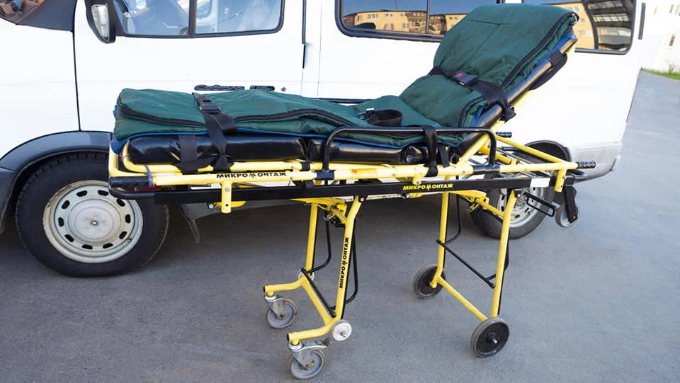 Padded stretcher positioned alongside the side door of a medical transport van